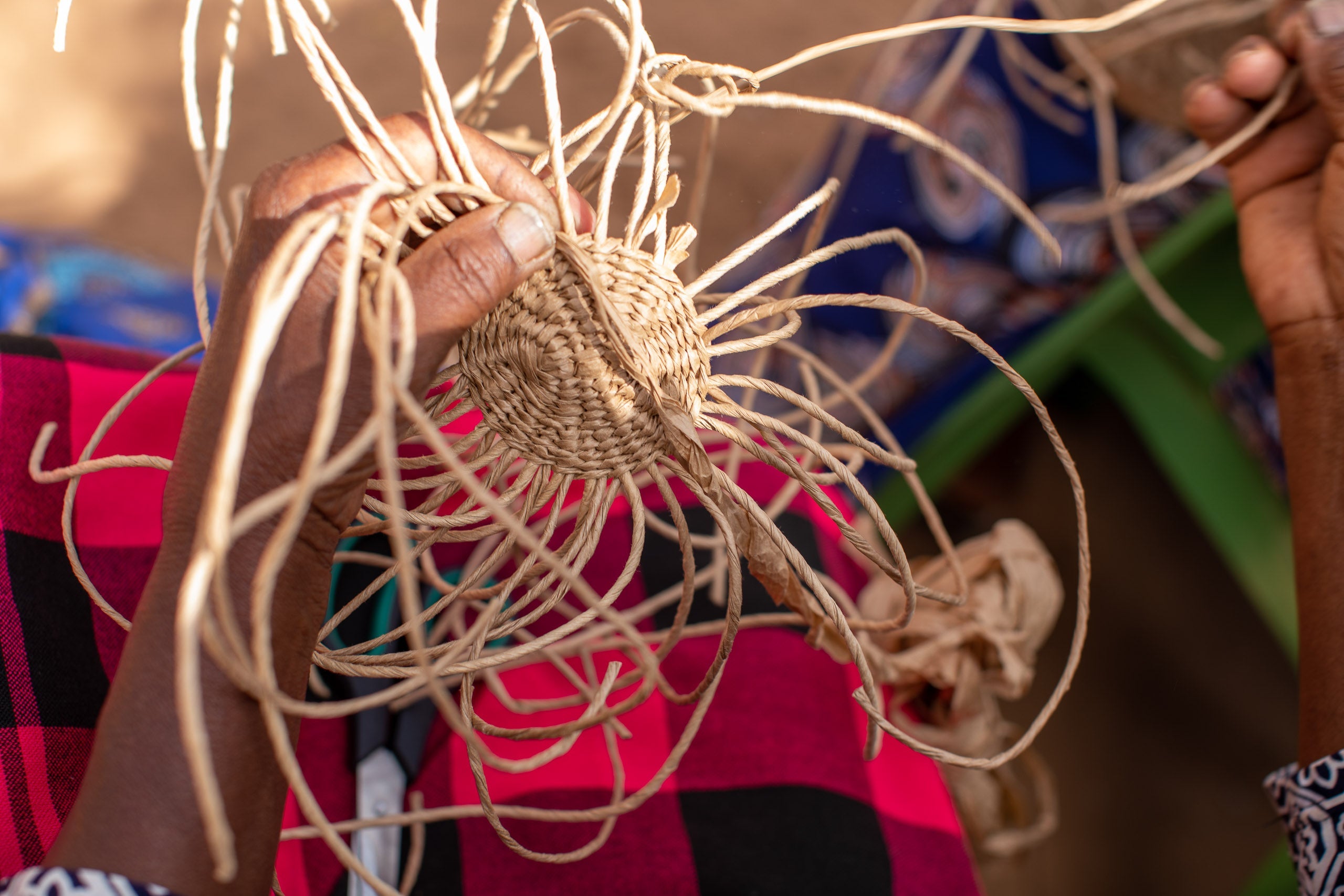 A brown Kiondo basket being woven by an artisan working with Mifuko