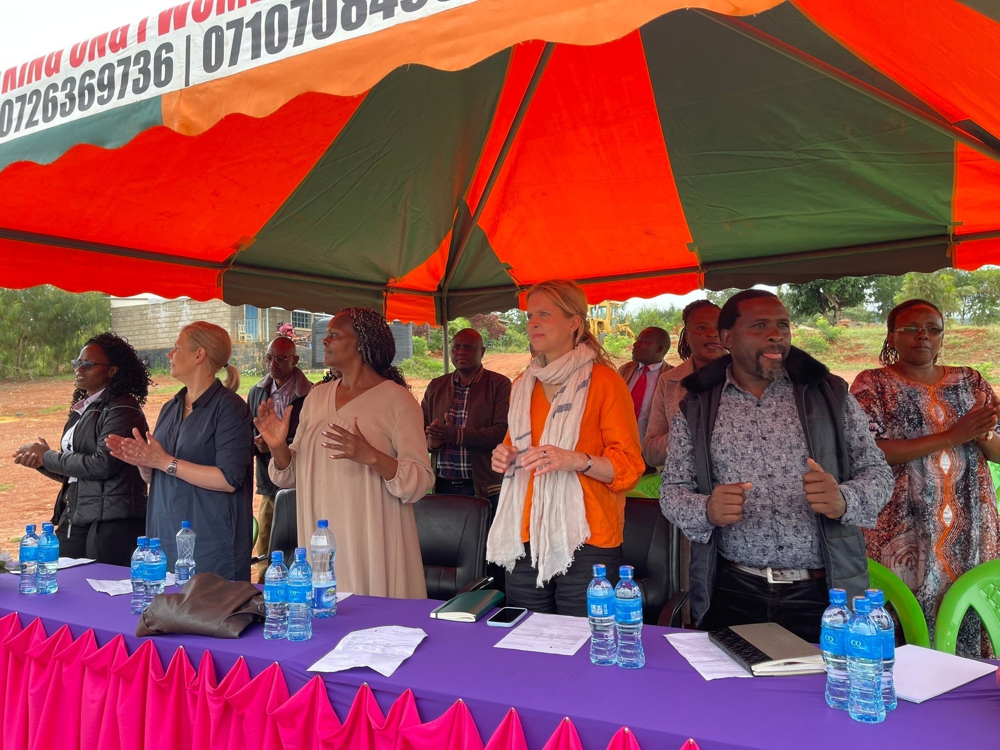 Women and men standing under a tent in Kenya