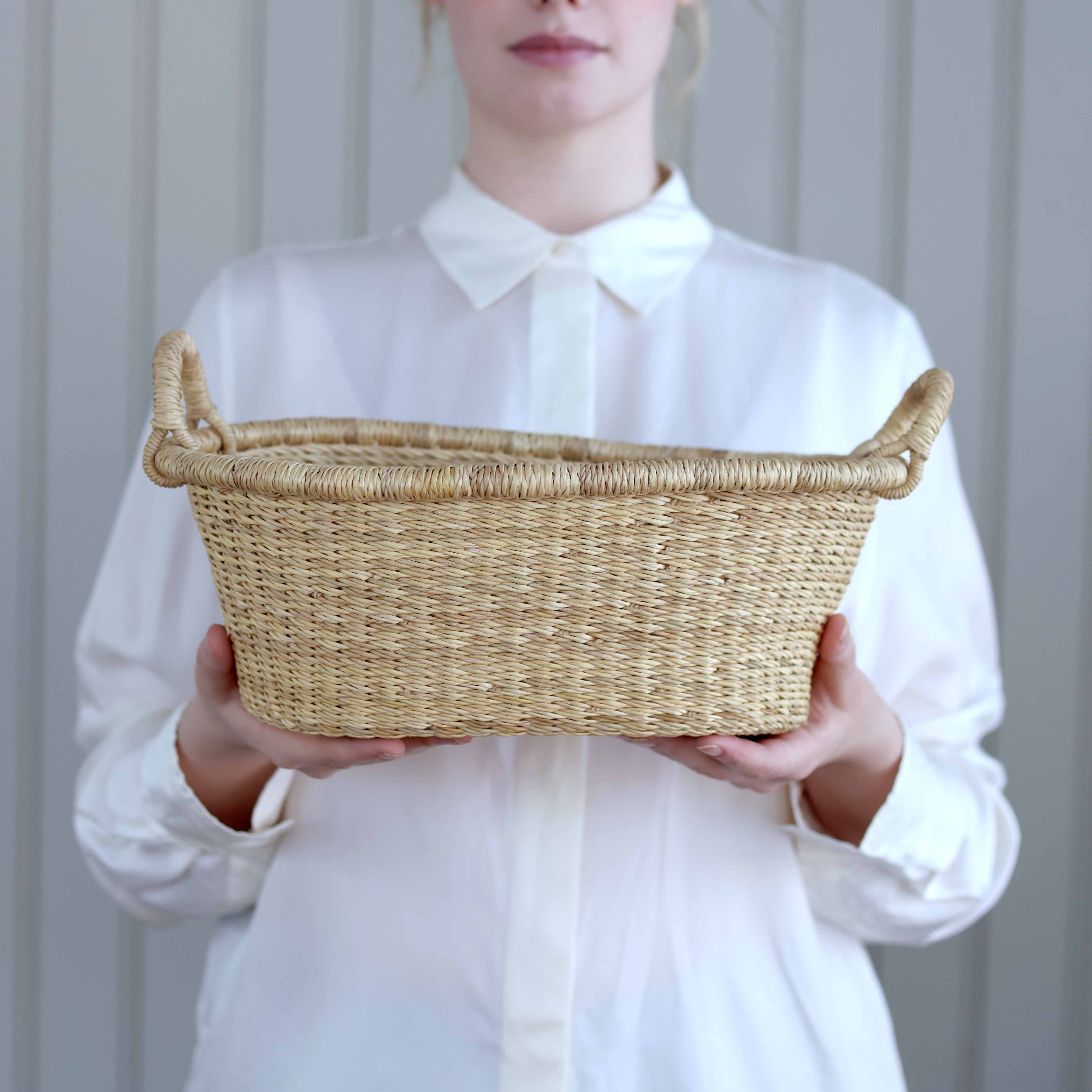 Person holding a woven basket against a plain background