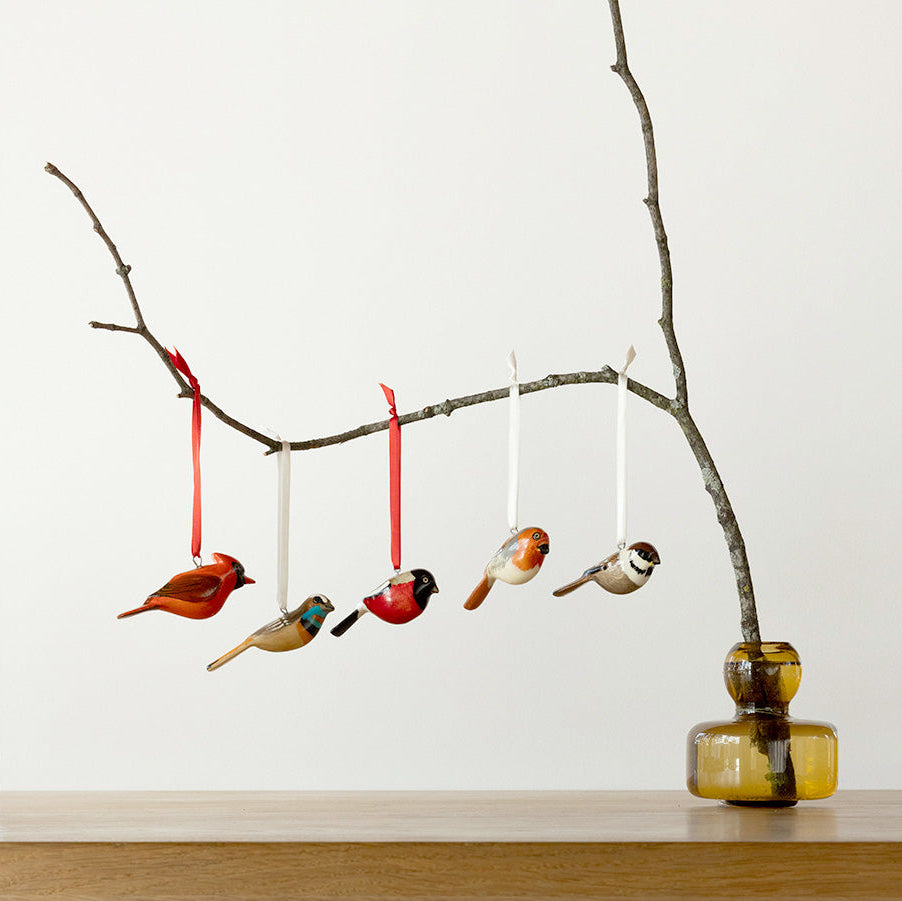 Decorative branch with hanging bird ornaments on a plain background