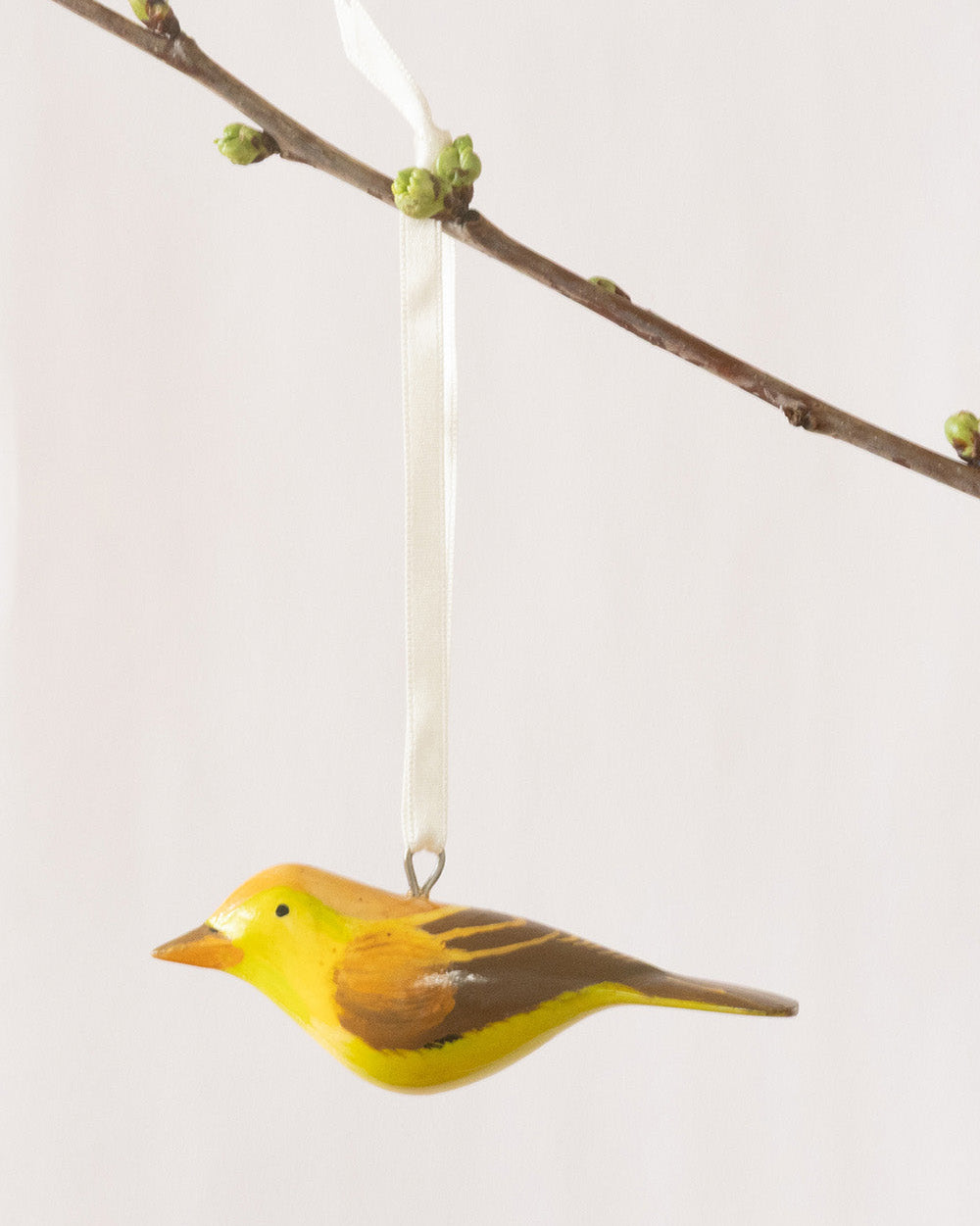 Decorative bird ornament hanging from a branch on a light gray background