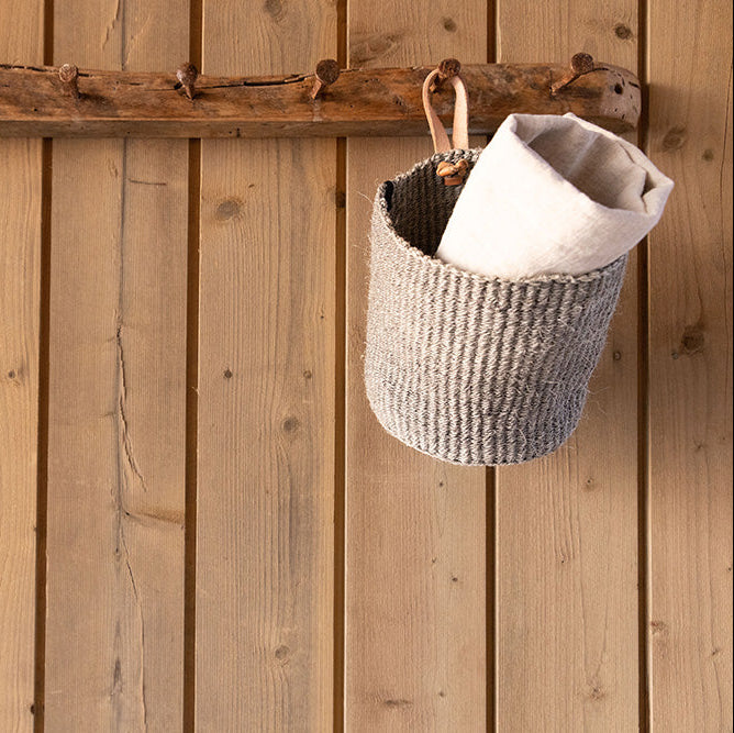 Woven basket with a white item hanging on a wooden wall with hooks