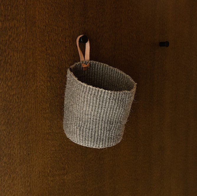 Woven basket with leather handle hanging on a wooden surface