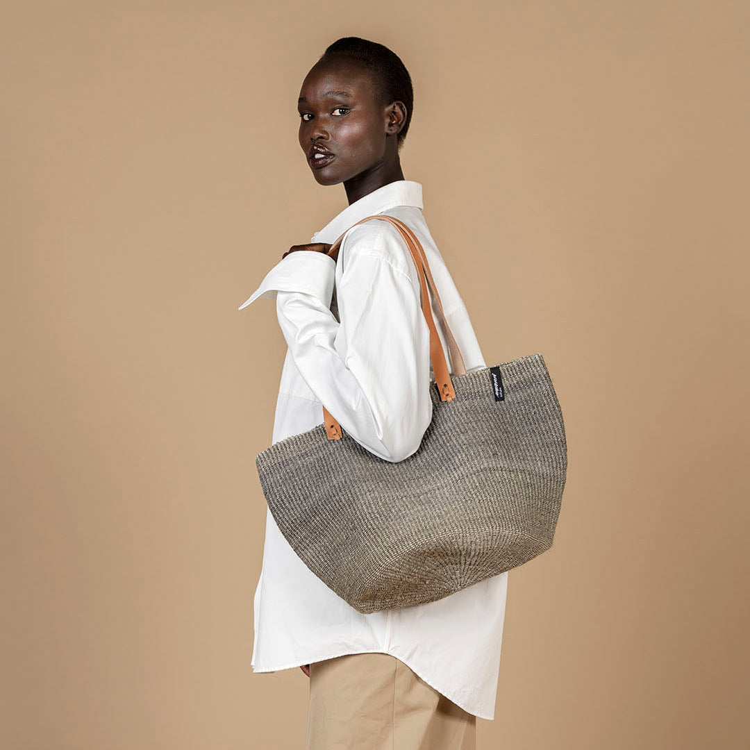 Person holding a woven bag against a beige background