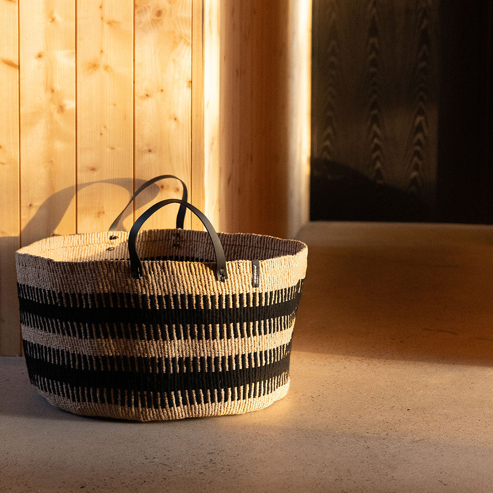 Woven basket with black and white pattern on a wooden floor
