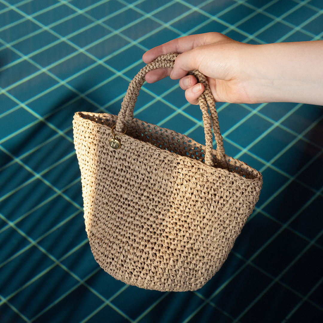 Hand holding a woven basket against a blue tiled background