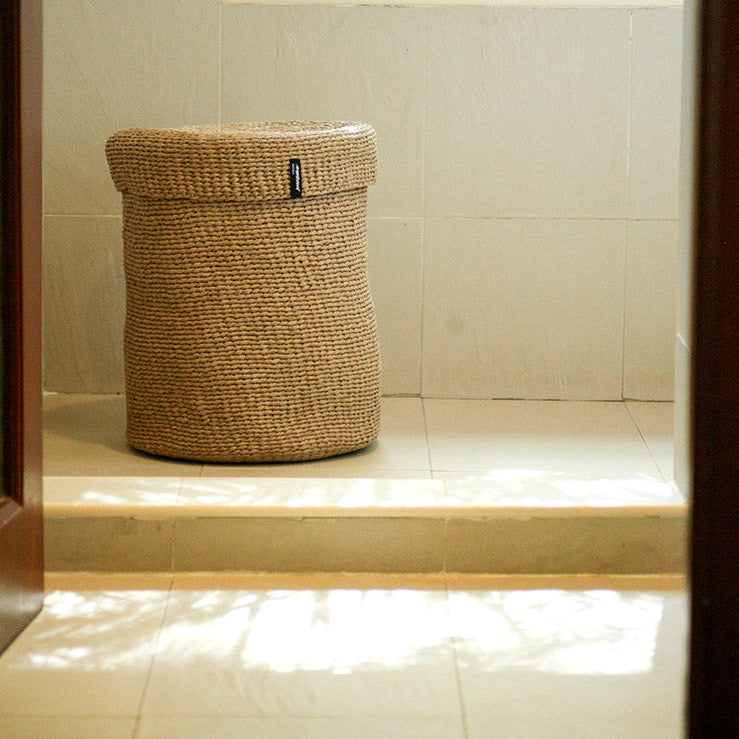 Woven basket with a lid on a tiled floor with a neutral color palette