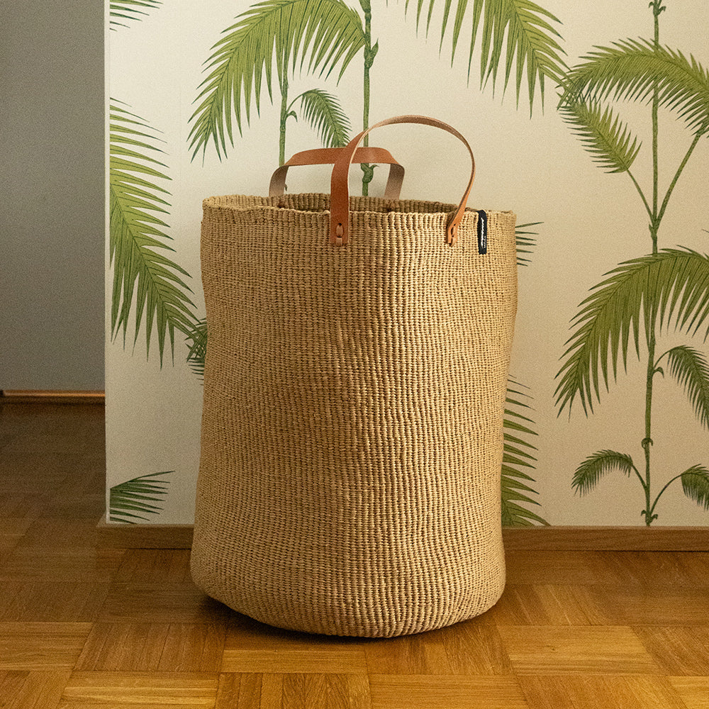 big brown basket in front of palm tapestry