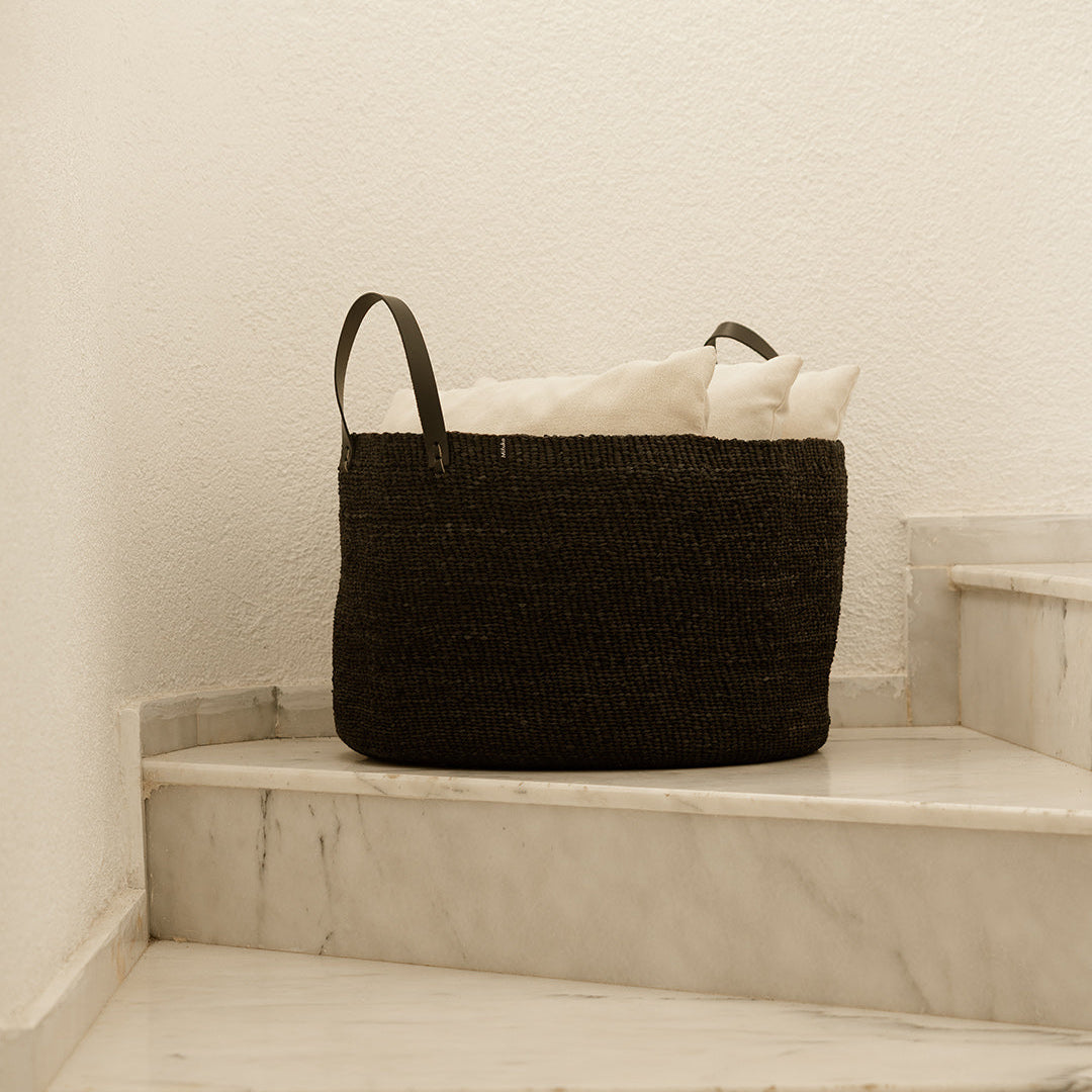 Black woven basket with handles on a marble staircase