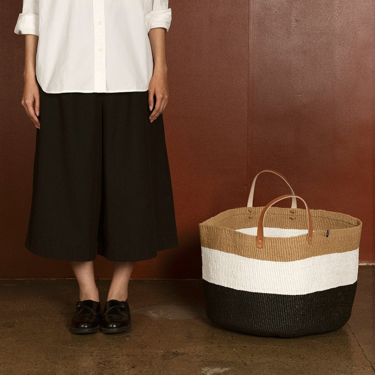 The Kiondo floor basket in Duo Black is a stunning and functional storage solution that seamlessly blends traditional craftsmanship with modern design. Handwoven by skilled artisans, this extra-large basket is crafted from a durable mix of FSC-certified paper and recycled plastic, ensuring it is lightweight, strong, and environmentally friendly.