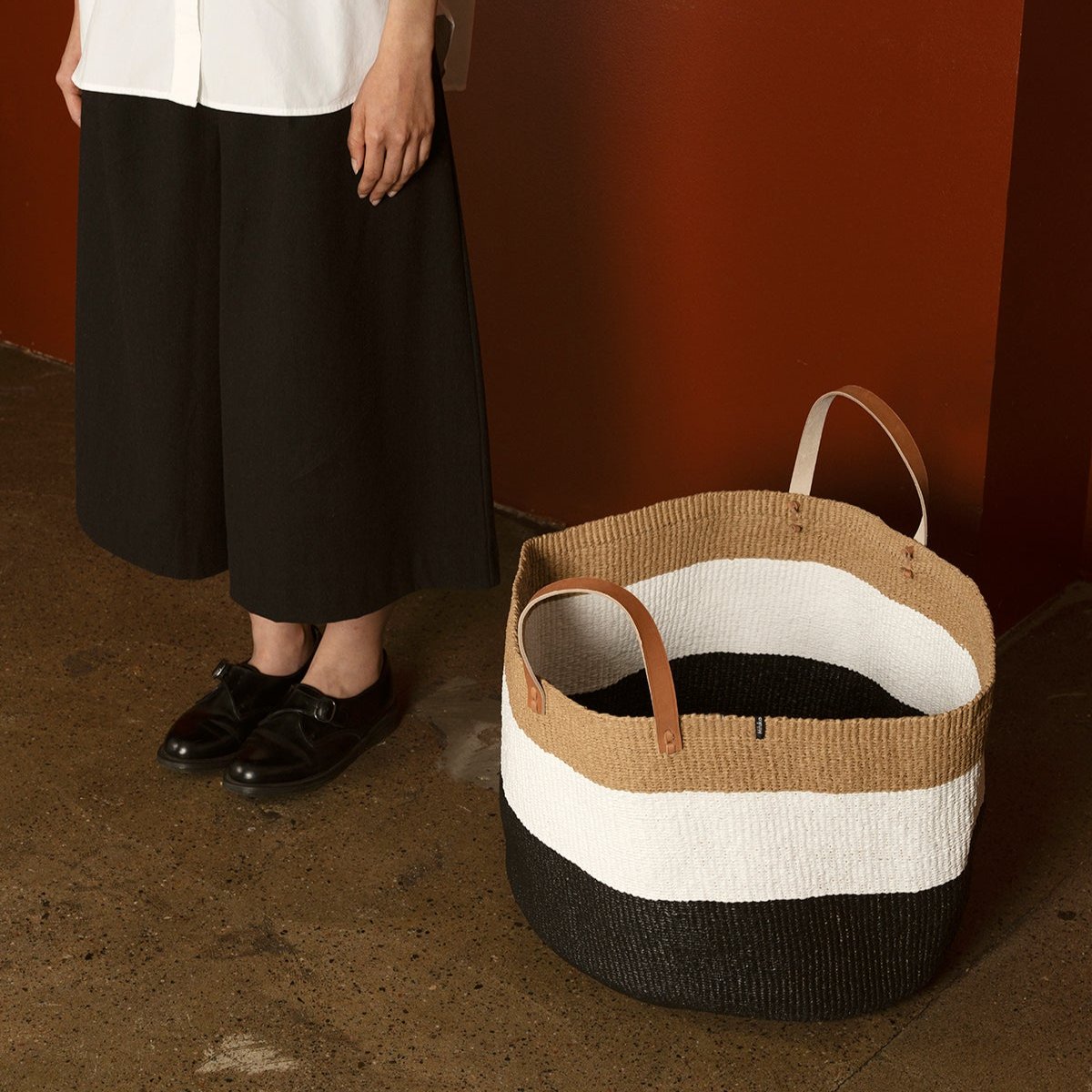 The Kiondo floor basket in Duo Black is a stunning and functional storage solution that seamlessly blends traditional craftsmanship with modern design. Handwoven by skilled artisans, this extra-large basket is crafted from a durable mix of FSC-certified paper and recycled plastic, ensuring it is lightweight, strong, and environmentally friendly.