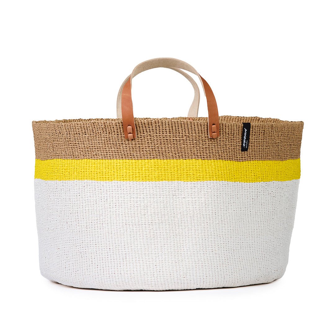 The Kiondo Floor Basket with a vibrant top stripe in yellow is a statement piece that combines style, functionality, and sustainability. Handwoven by skilled artisans, this extra-large basket is crafted from a unique blend of FSC-certified paper and upcycled plastic, making it lightweight yet durable.