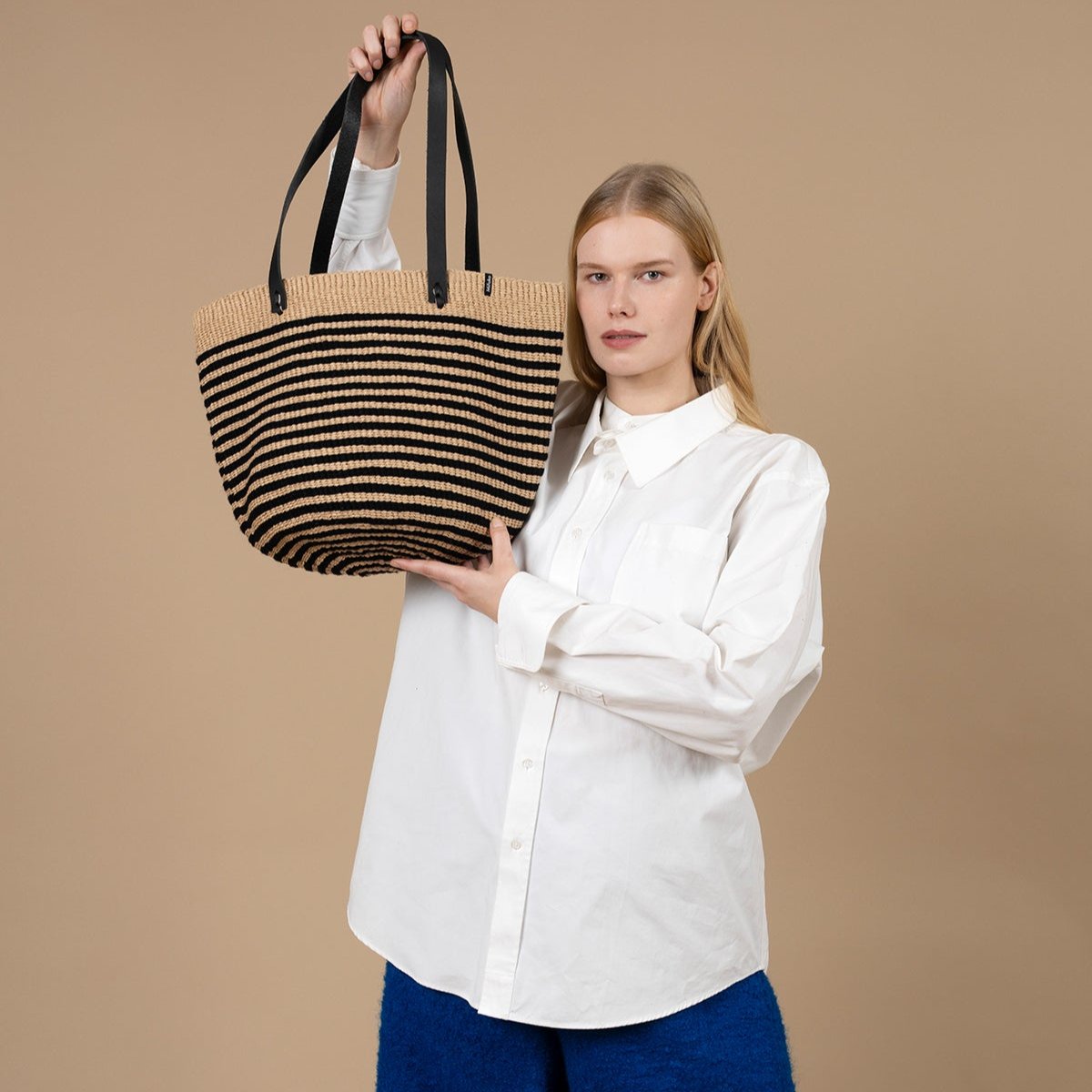 The Pamba shopper basket is a perfect blend of style, functionality, and sustainability. Handwoven with care, this medium-sized basket features a chic black thin stripe design, adding a touch of sophistication to its timeless look.
