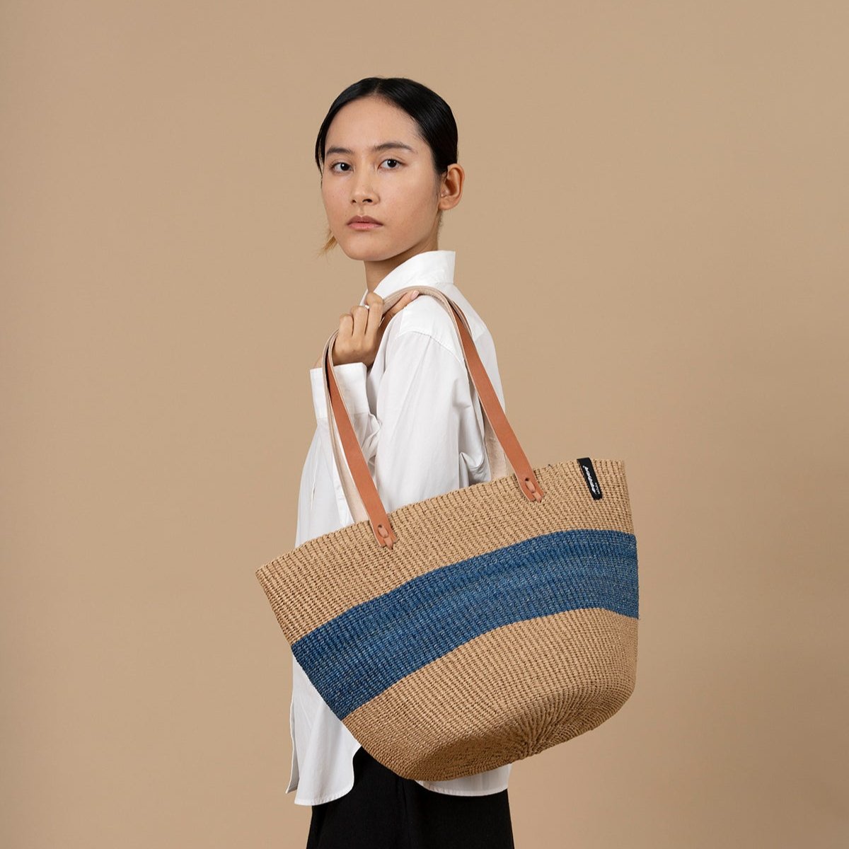 The Majani shopper basket is a beautiful and versatile accessory, handwoven with care using a combination of lightweight, durable paper fiber and soft, eco-friendly banana fiber