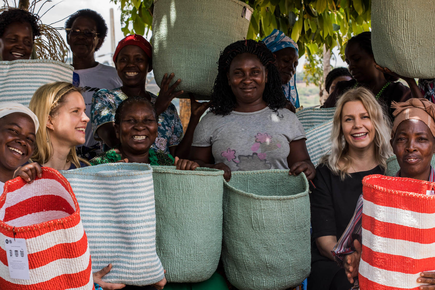 Minna and Mari with a group of artisans under a tree