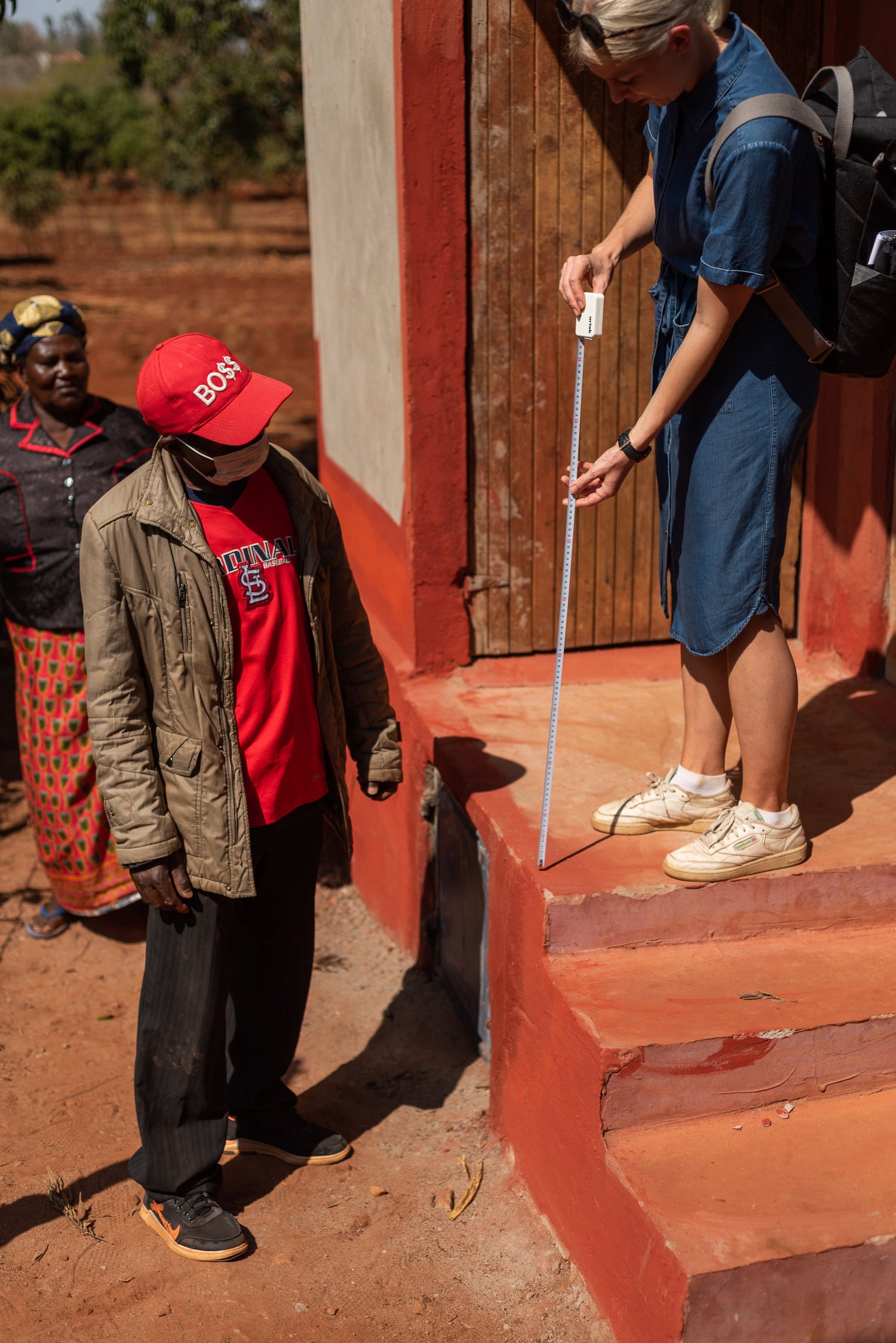 Vilma Autio with a measuring tape and a constructor in the stairs of a dry toilet