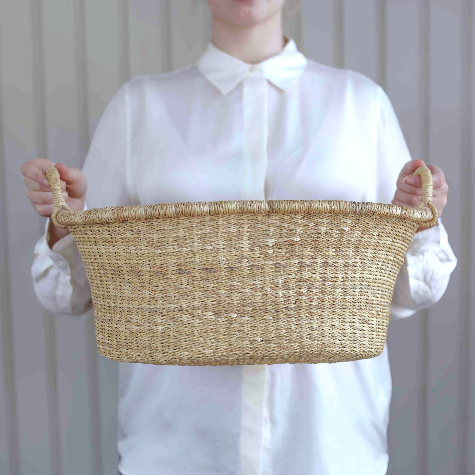 Person holding a woven basket against a plain background