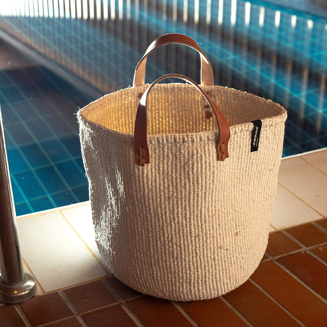 Beautiful handmade white basket with leather handles by the pool.