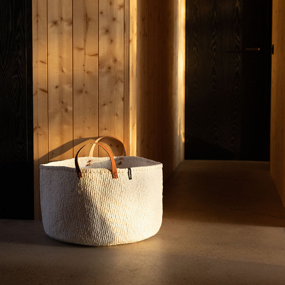 Woven basket with leather handle on a wooden floor
