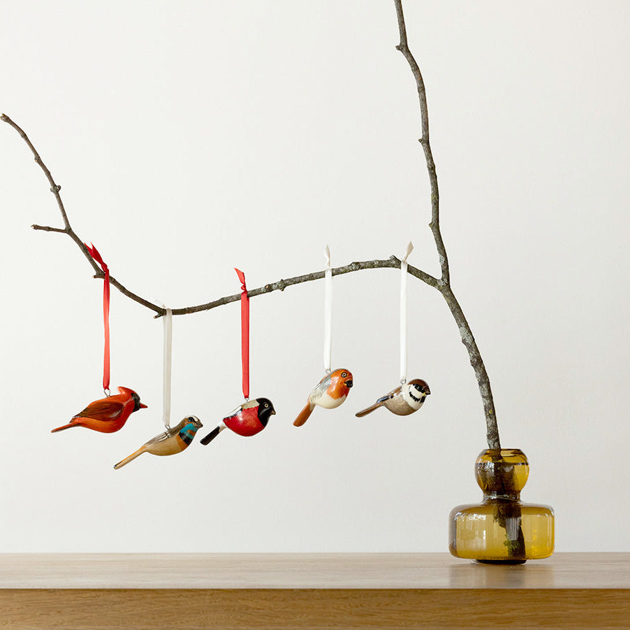 Decorative branch with hanging bird ornaments on a plain background