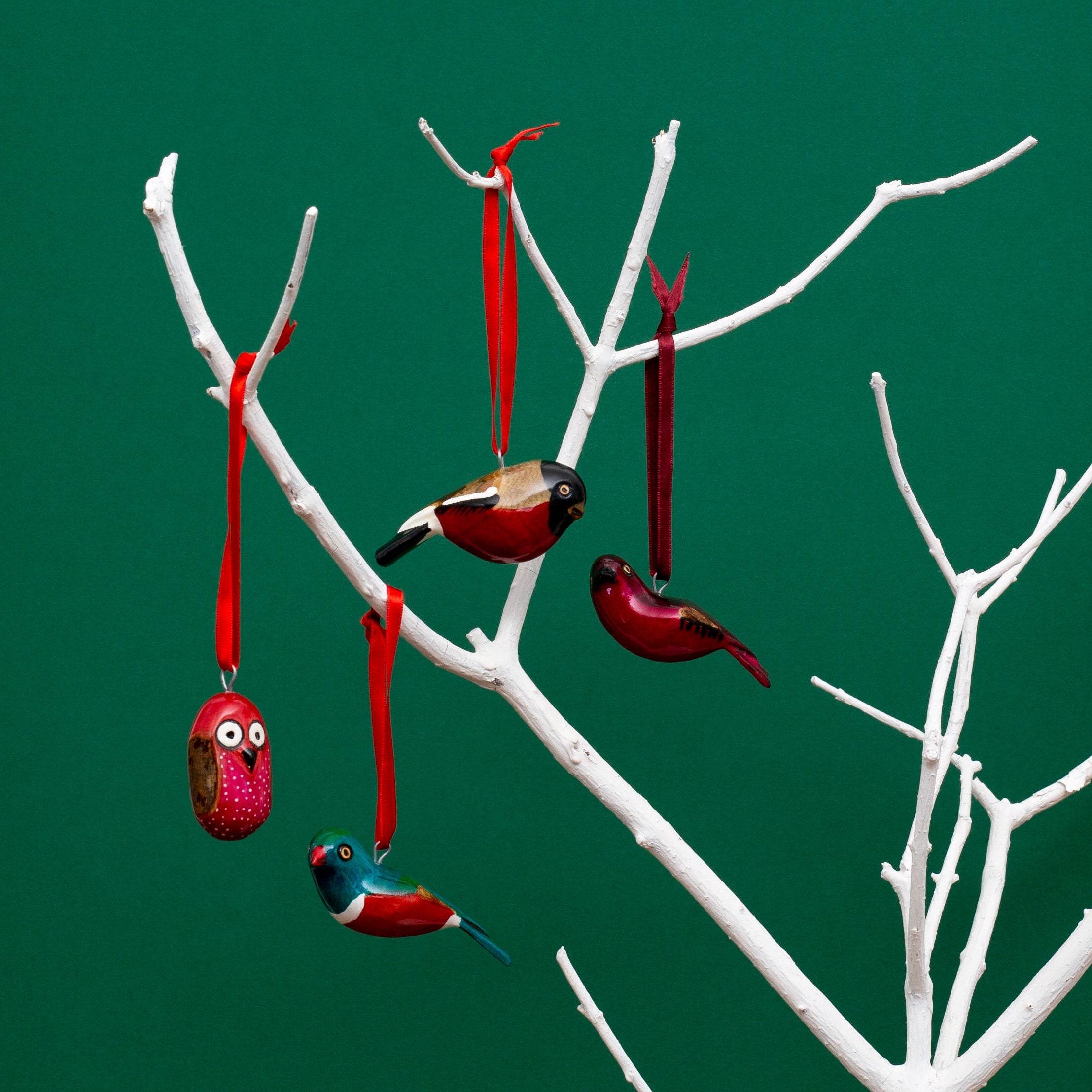 Decorative bird ornaments hanging from a branch against a green background