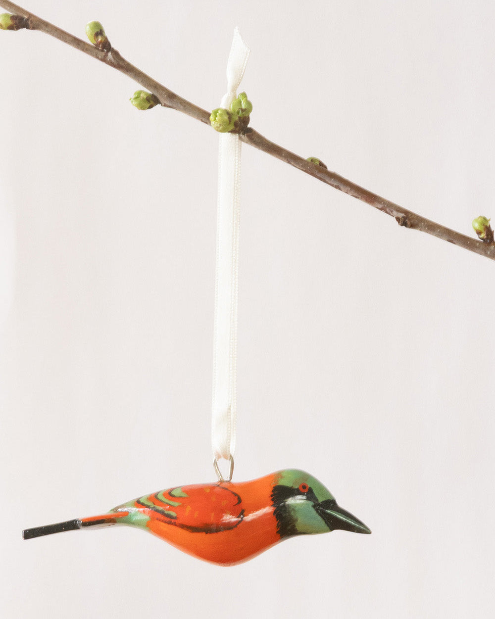 Decorative bird ornament hanging from a branch with a white background