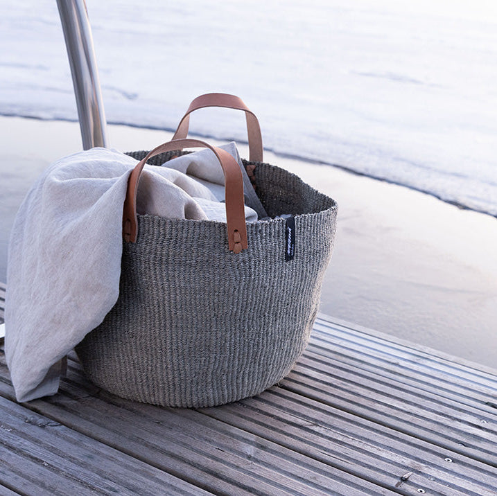 Woven basket with leather handles on a wooden surface