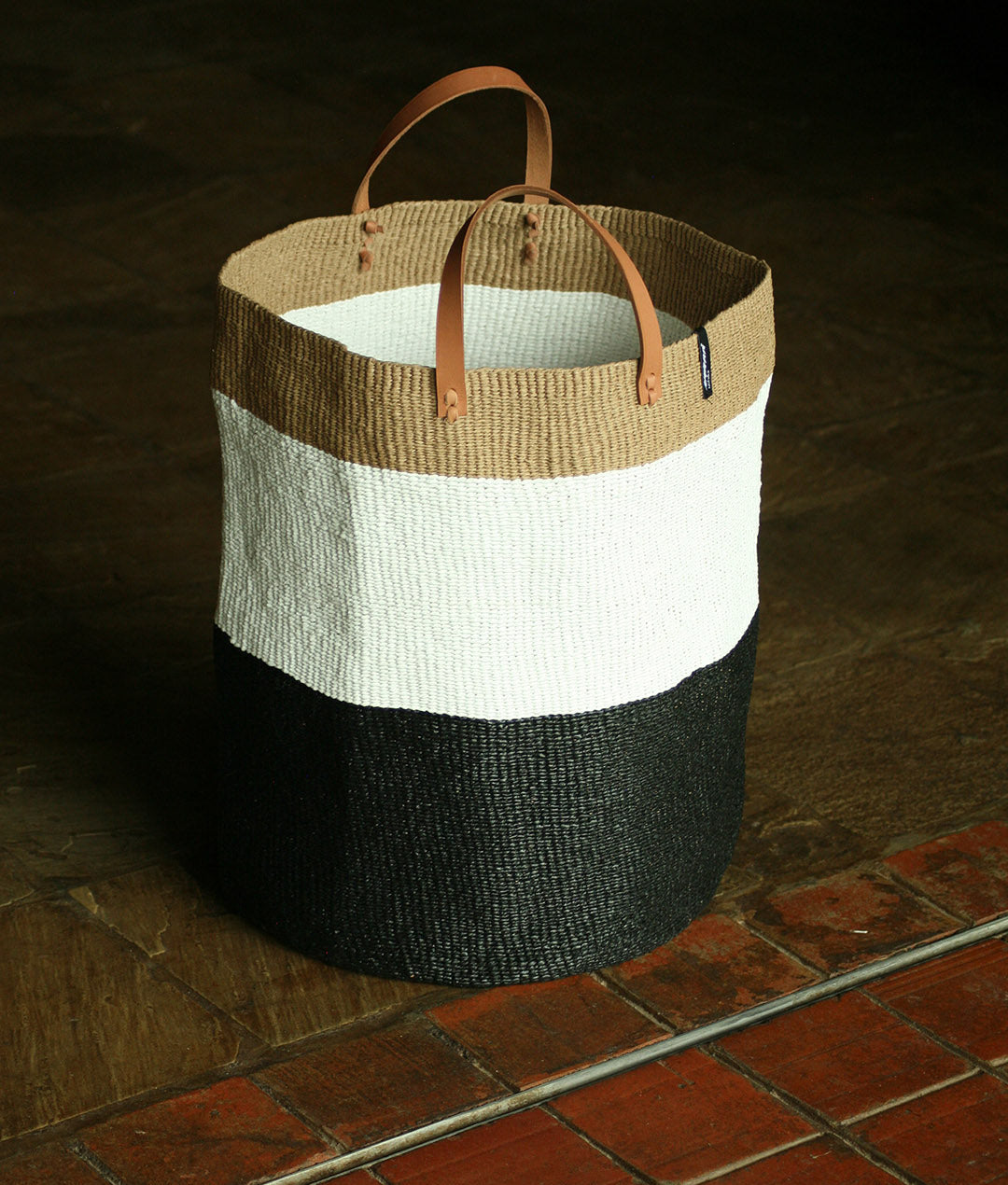 black and white laundry floor basket, handmade with leather handles.