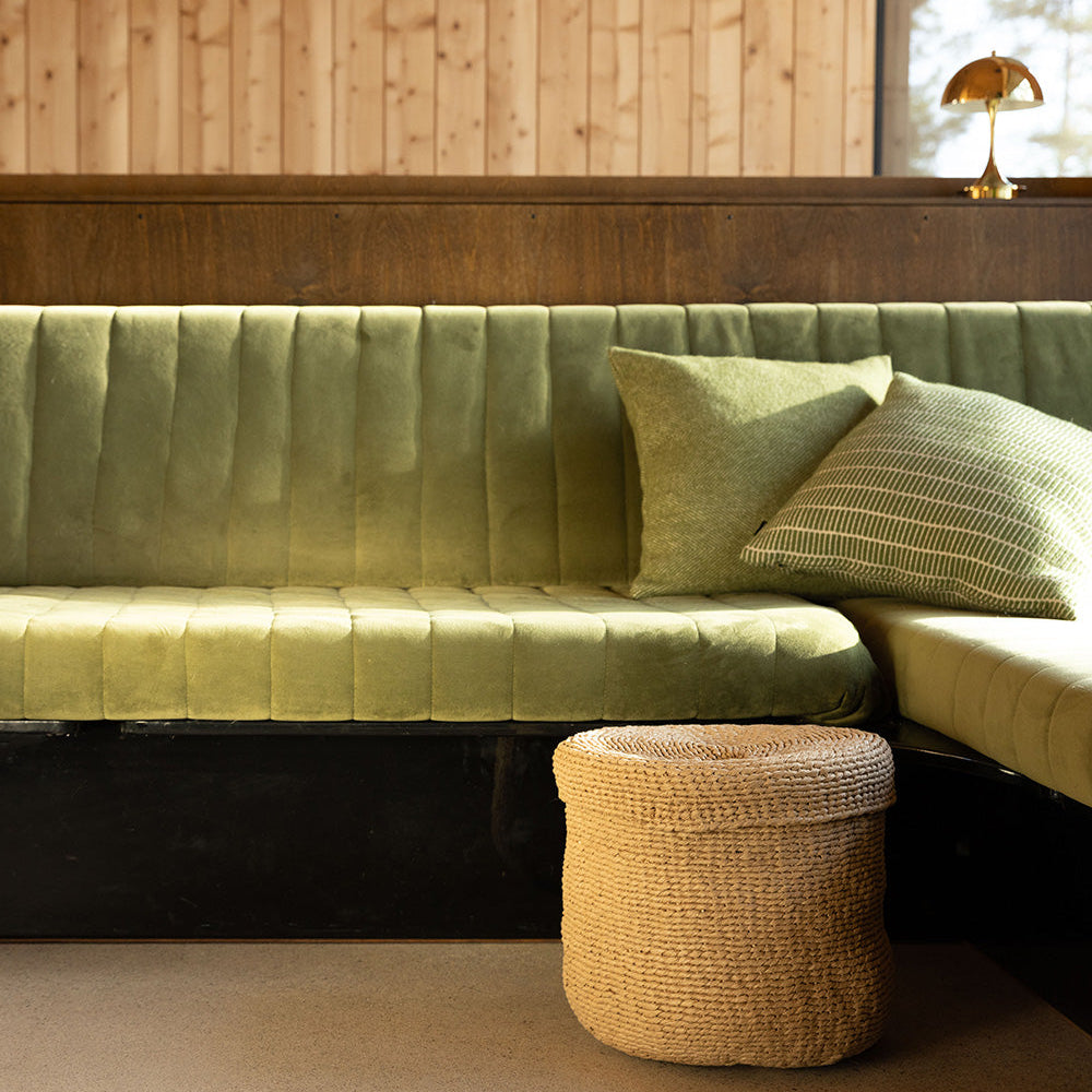 brown basket with lid in front of green sofa