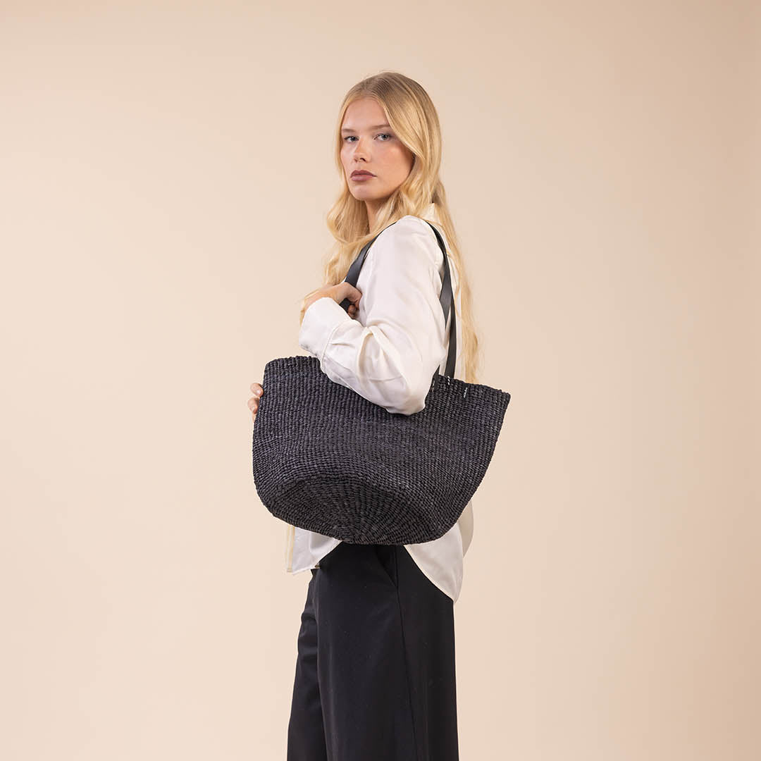 Woman holding a textured black handbag against a beige background
