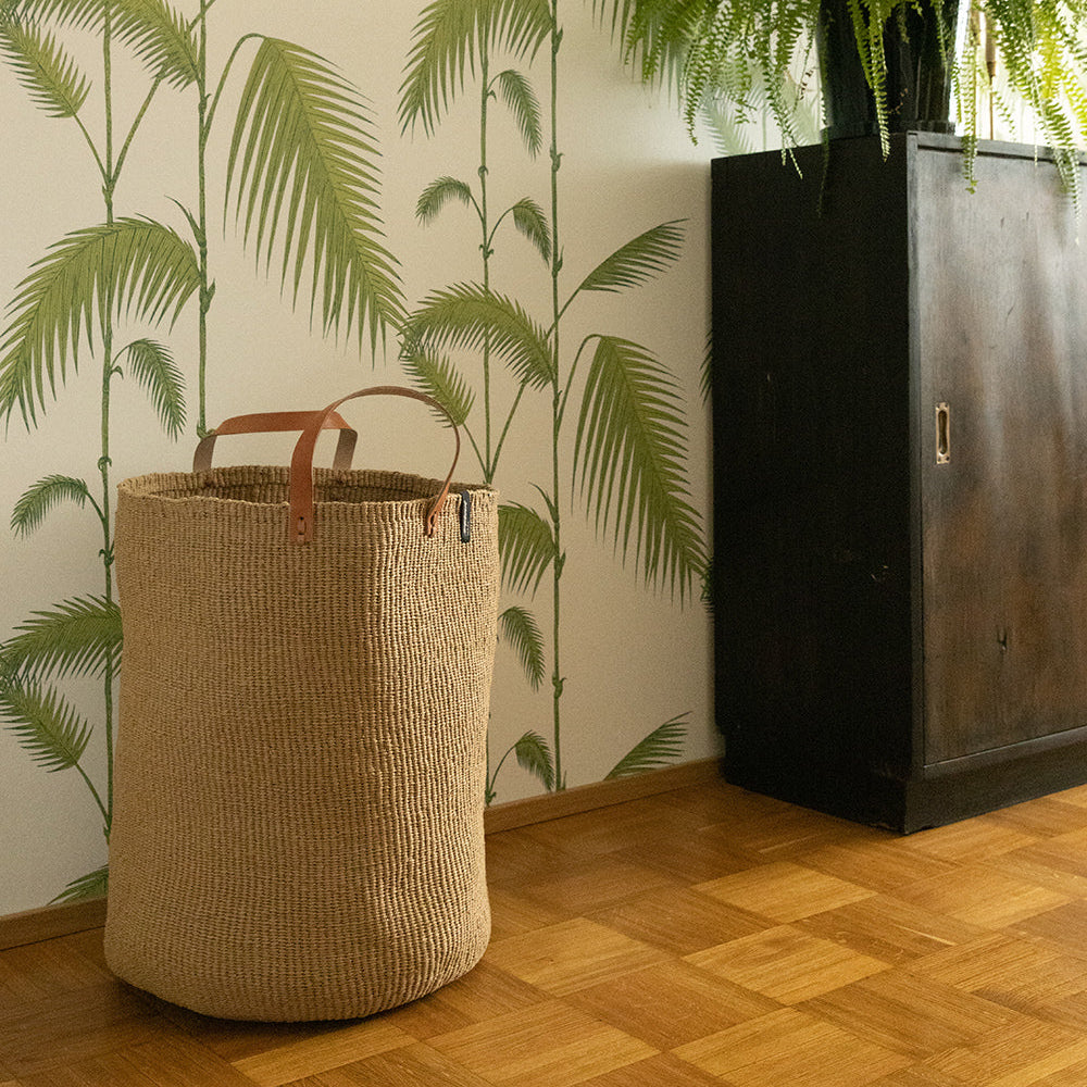 big brown basket in front of palm tapestry and fern