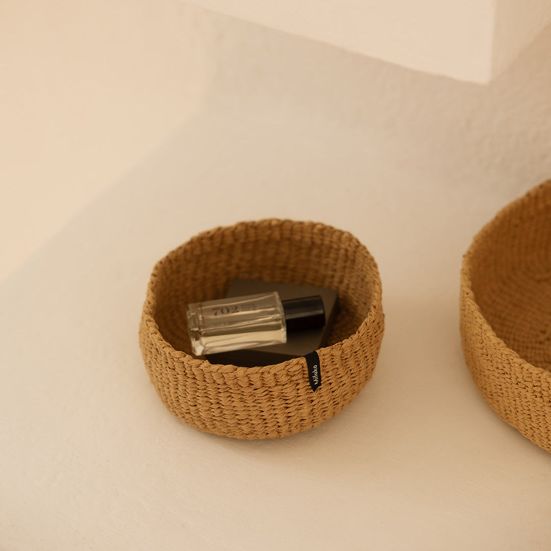 Woven basket with a small bottle inside on a neutral background