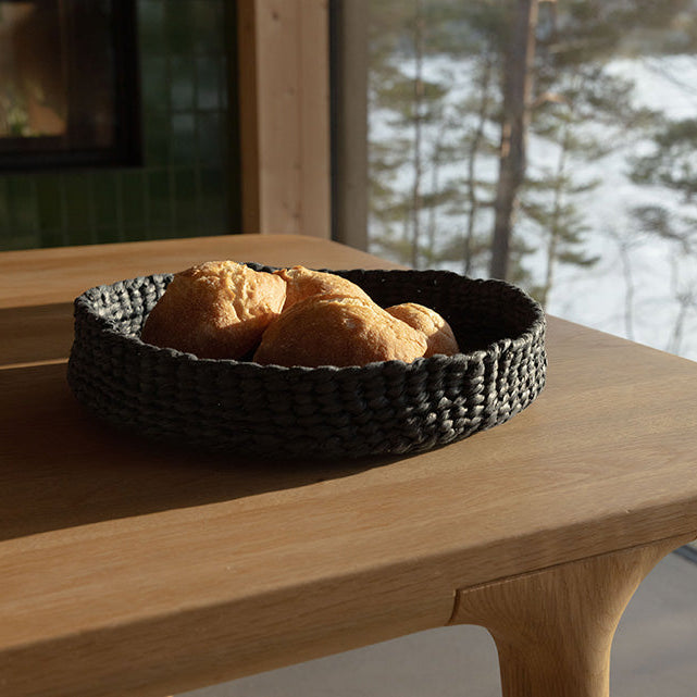 Bread in a woven basket on a wooden table with a snowy landscape outside
