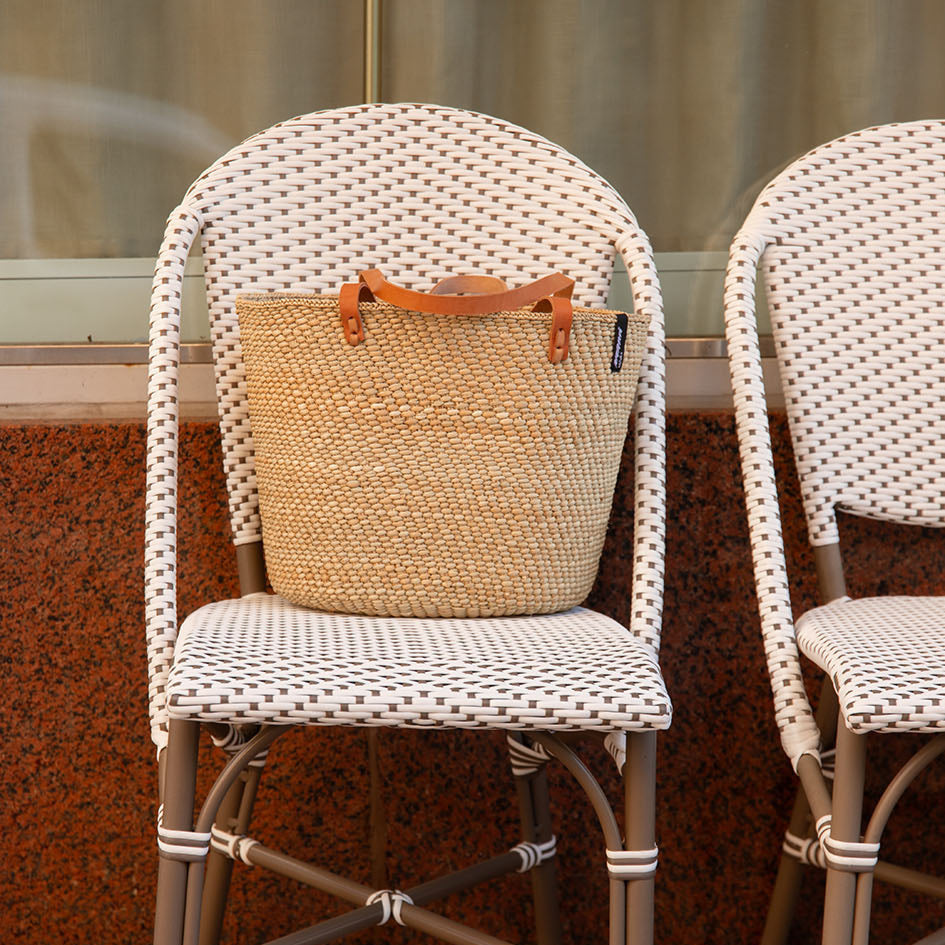 Beige  natural  handwoven tote bag with brown leather handles on a white background fair trade