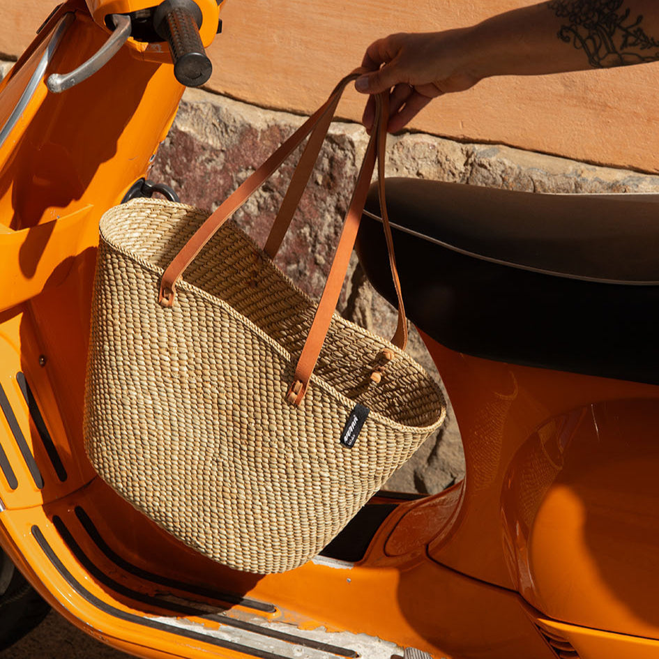 Beige  natural  handwoven tote bag with brown leather handles on a white background fair trade