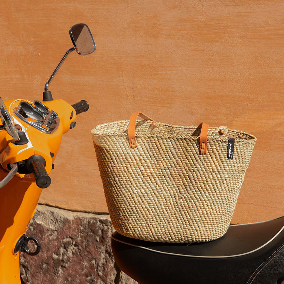 Beige  natural  handwoven tote bag with brown leather handles on a white background fair trade
