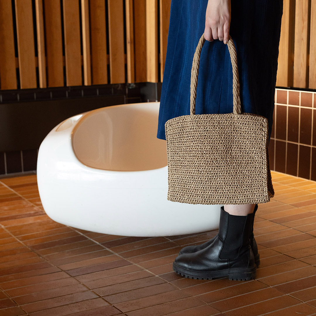 Woman with beautiful blue dress and crocheted brown bag
