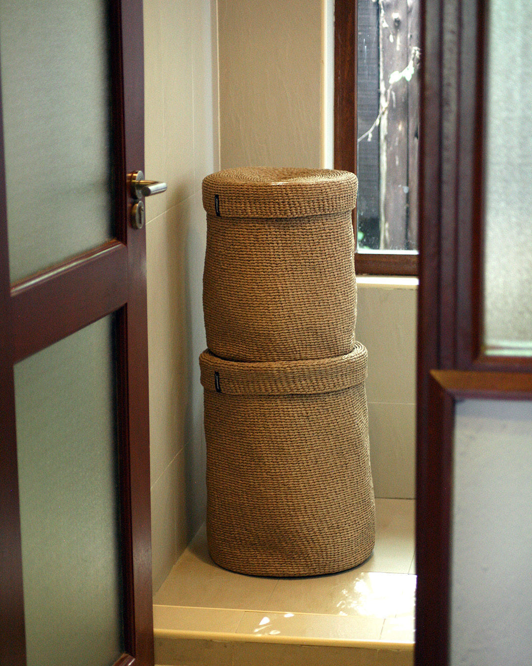 Stack of woven baskets in a bathroom with a door and window.